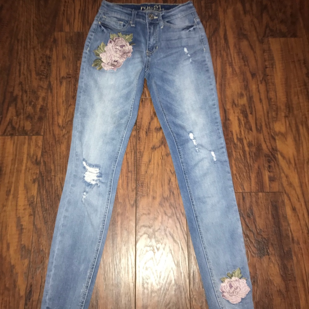 Light blue jeans, pink rose on them.